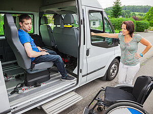 Kind im Rollstuhl wird von einem Großraumtaxi abgeholt 